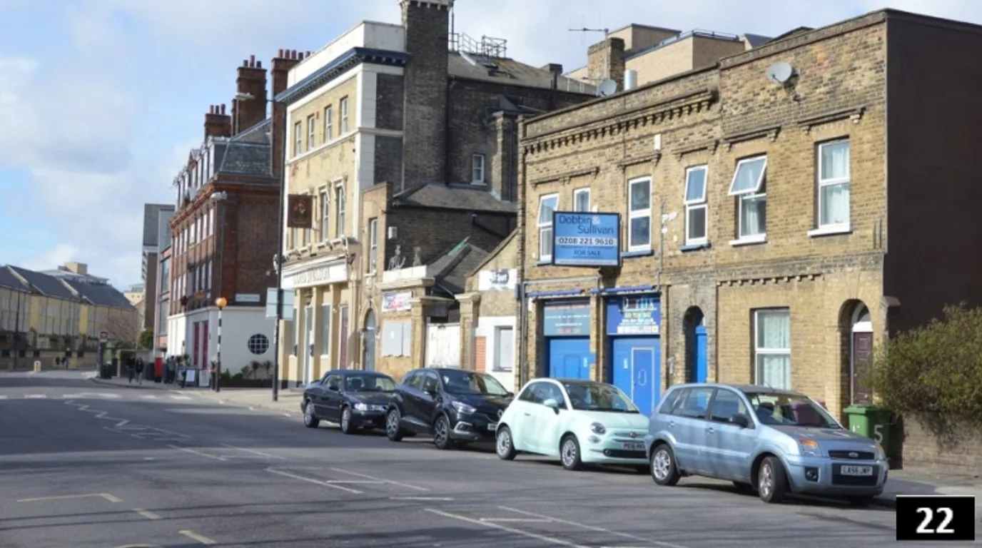 1990s Poplar High Street street frontage condition with parked cars, blue shopfronts and retained brick buildings before restoration concept CGI