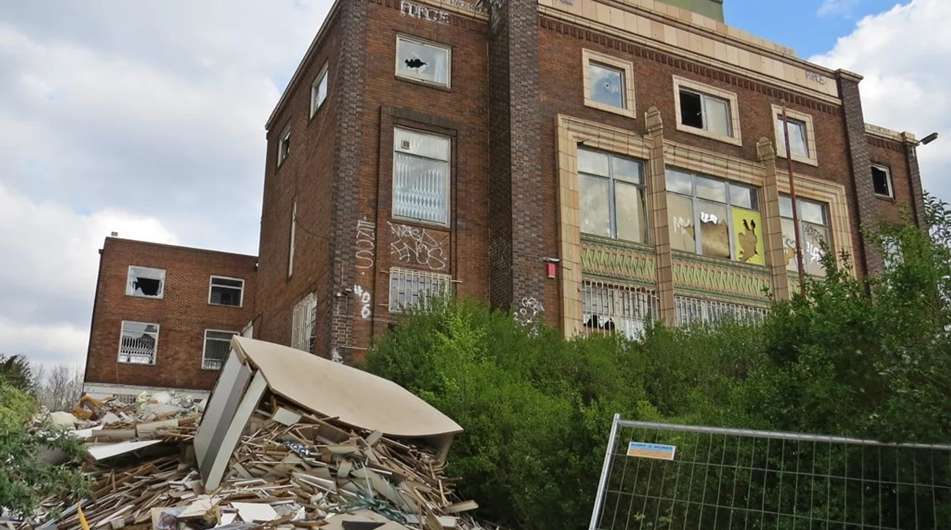 Existing dilapidated Martindale House on Poplar High Street with broken windows, graffiti, and street rubble before concept visualisation